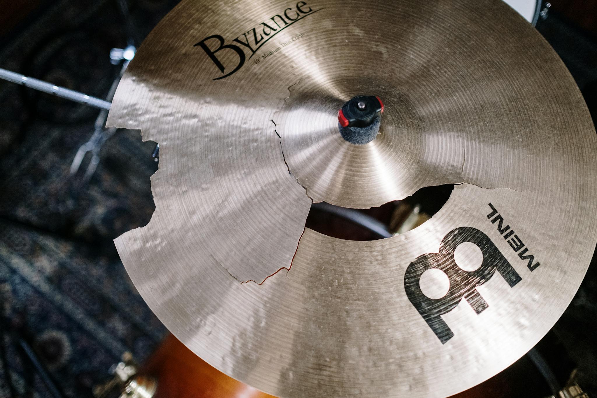 Detailed image of a cracked metal cymbal on a drum set, capturing its intricate texture.